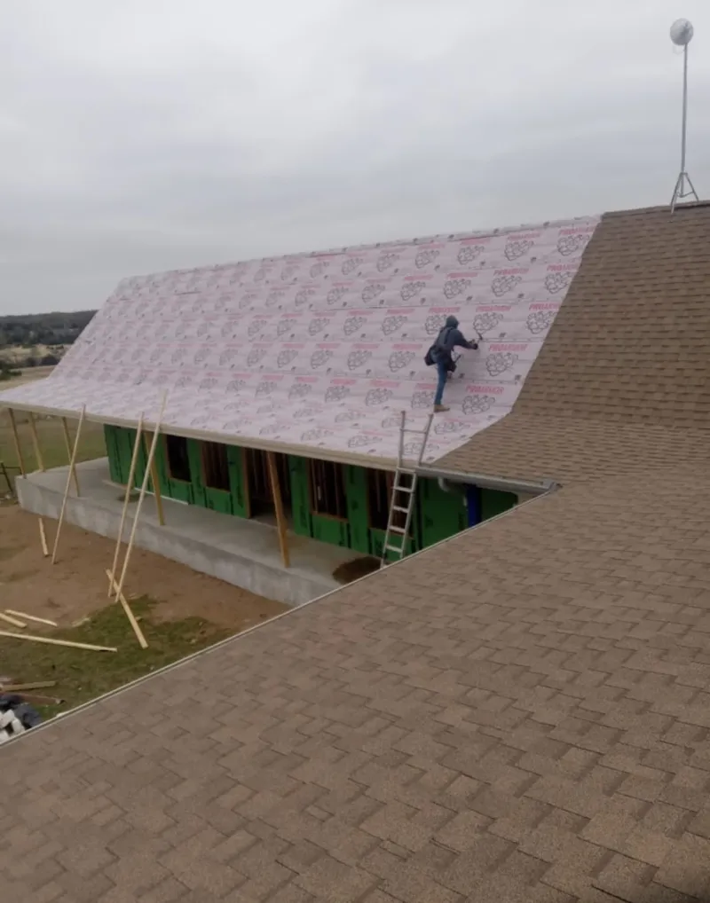Worker preparing underlayment for a metal roof installation in Rusk